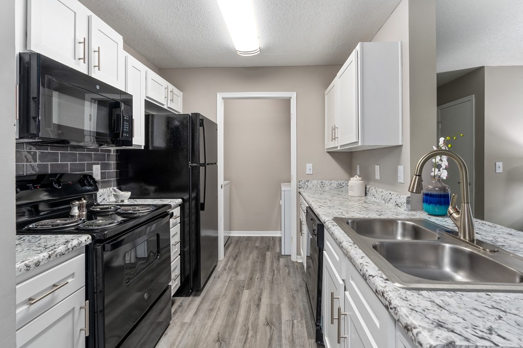 a kitchen with white cabinets and black appliances