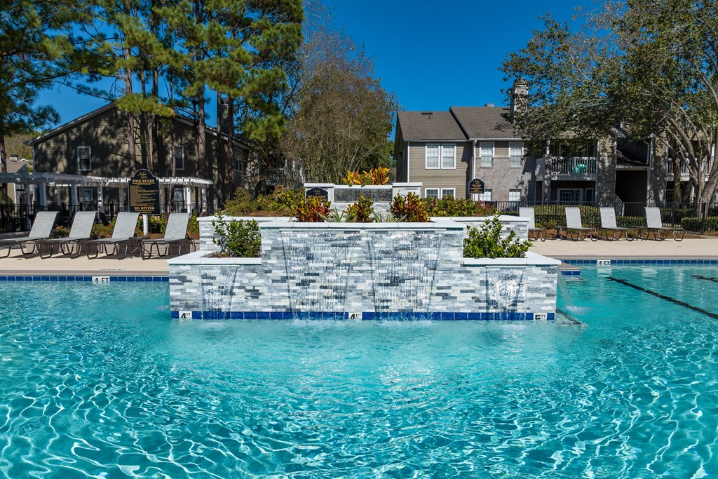 a swimming pool with a stone wall in front of a house