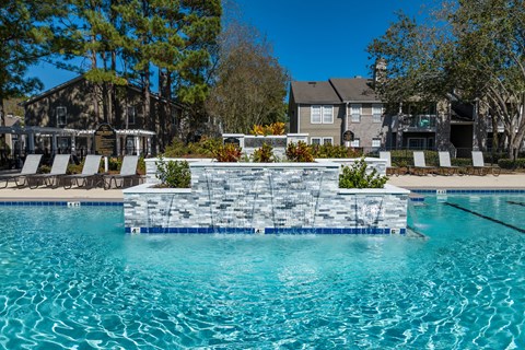 a swimming pool with a stone wall in front of a house