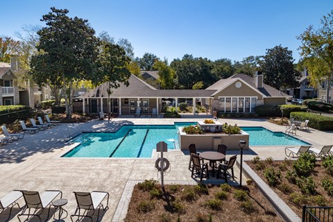 a swimming pool with patio furniture and a house in the background
