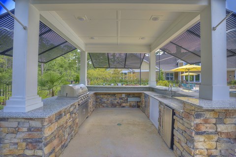 a covered outdoor kitchen with a grill and a sink