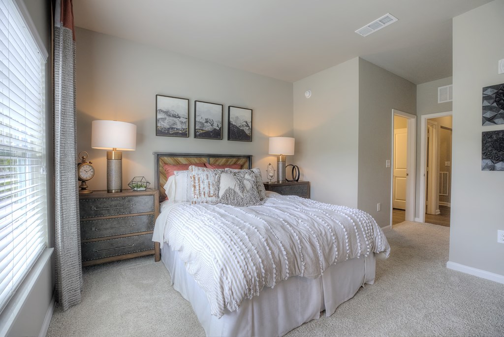 Furnished model bedroom with a window and carpet flooring at Lullwater at Blair Stone apartments for rent