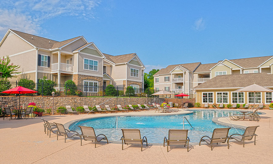 a swimming pool with chairs in front of an apartment building
