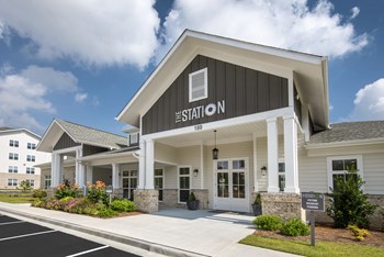 Entrance of the leasing office and resident clubhouse with lush landscaping at the Station at Savannah Quarters in Pooler, GA - Photo Gallery 4