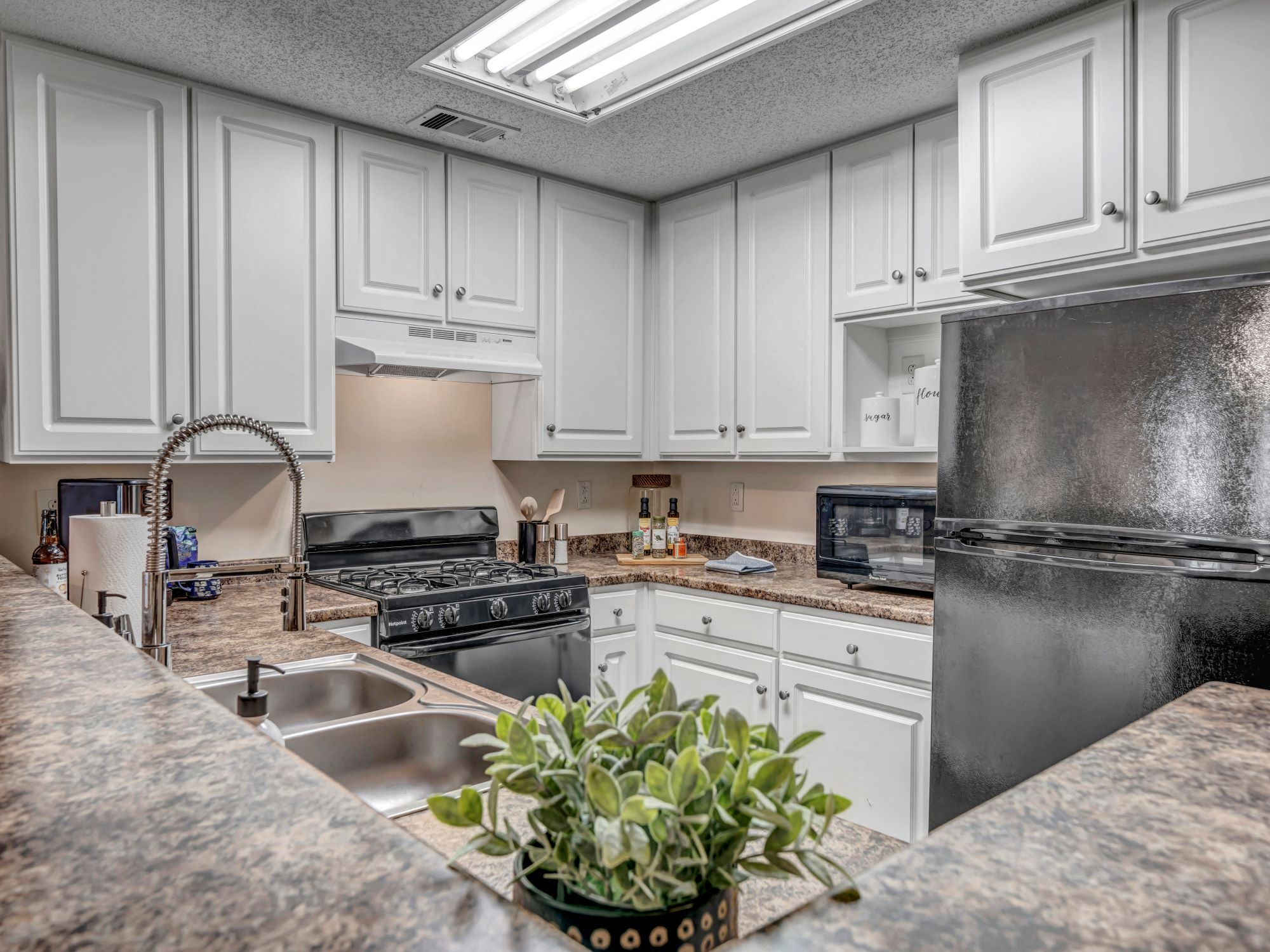 a kitchen with white cabinets and black appliances