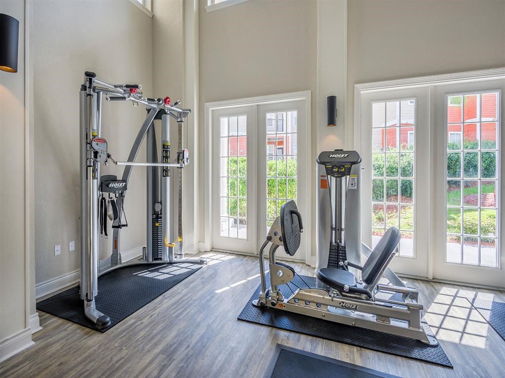 Premium fitness center with exercise equipment, padded flooring, tall windows, and high ceiling at Evergreen at Mahan in Tallahassee, FL