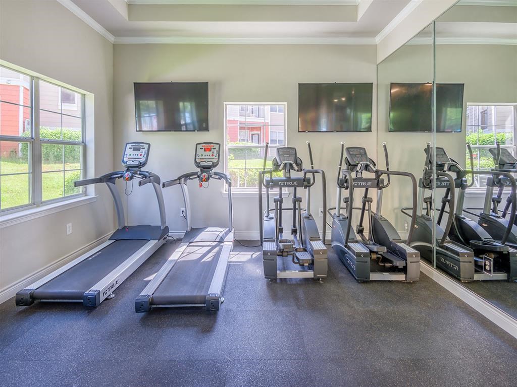 Premium fitness center with exercise machines, padded flooring, tall windows, and high ceiling at Evergreen at Mahan in Tallahassee, FL