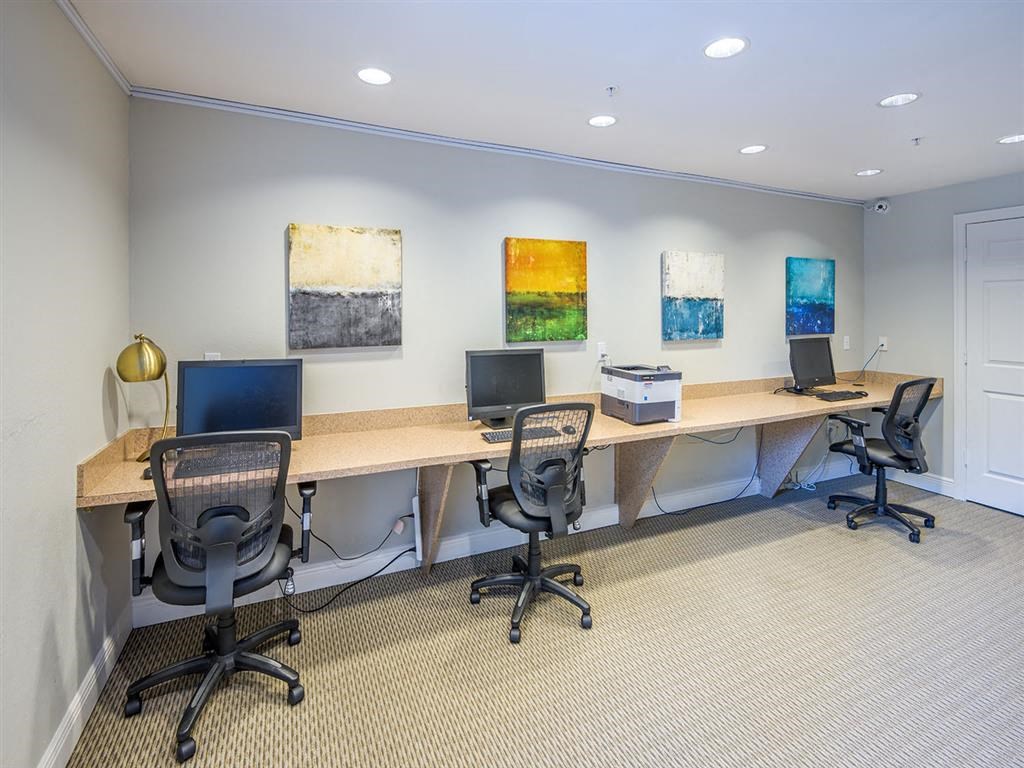 Tallahassee, FL apartment complex  business center with three computers, long desk, and printer at Evergreens at Mahan