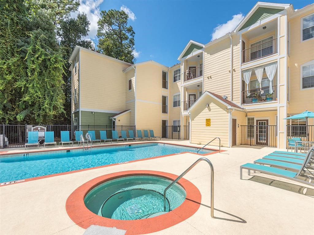 Hot tub spa next to resort-style swimming pool and sundeck at Evergreens at Mahan apartments in Tallahassee, FL
