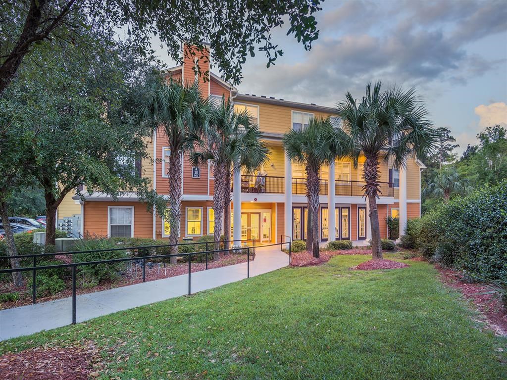Tallahassee FL apartment complex walkway with black railing and lush landscaping through Evergreens at Mahan
