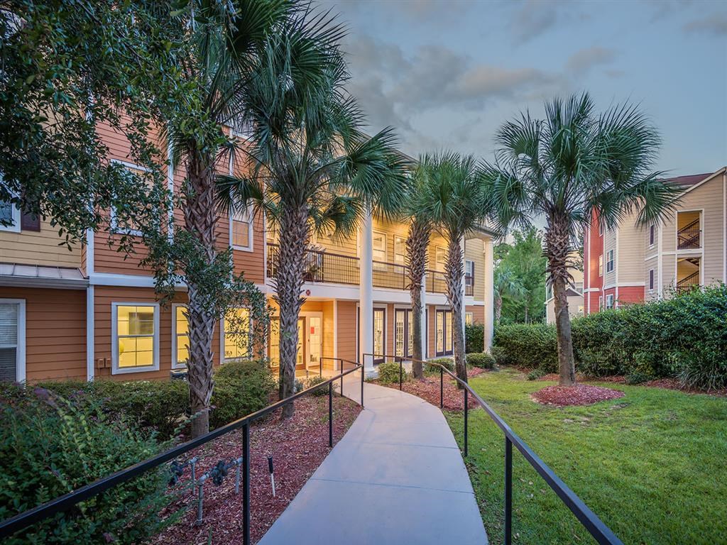 Walkway with black railing and lush landscaping through Evergreens at Mahan apartments in Tallahassee, FL