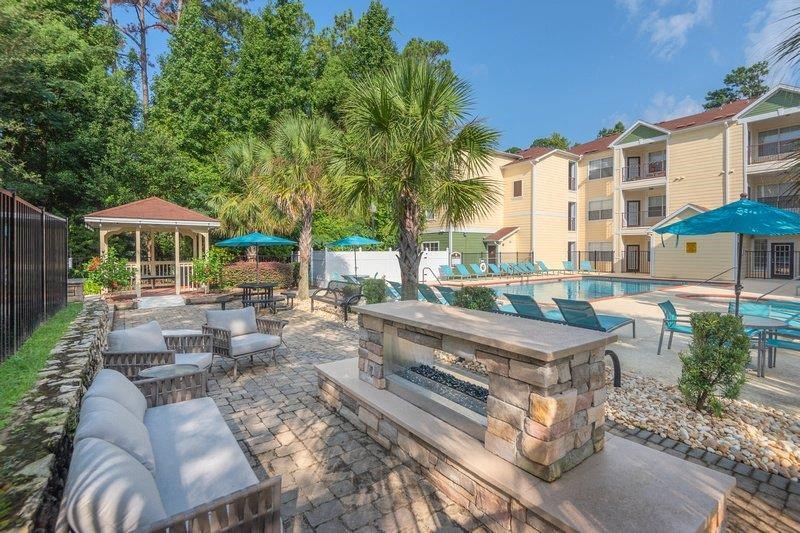 Cozy fire pit near pool with fireplace and several large lounging chairs at Evergreens at Mahan apartments in Tallahassee, FL