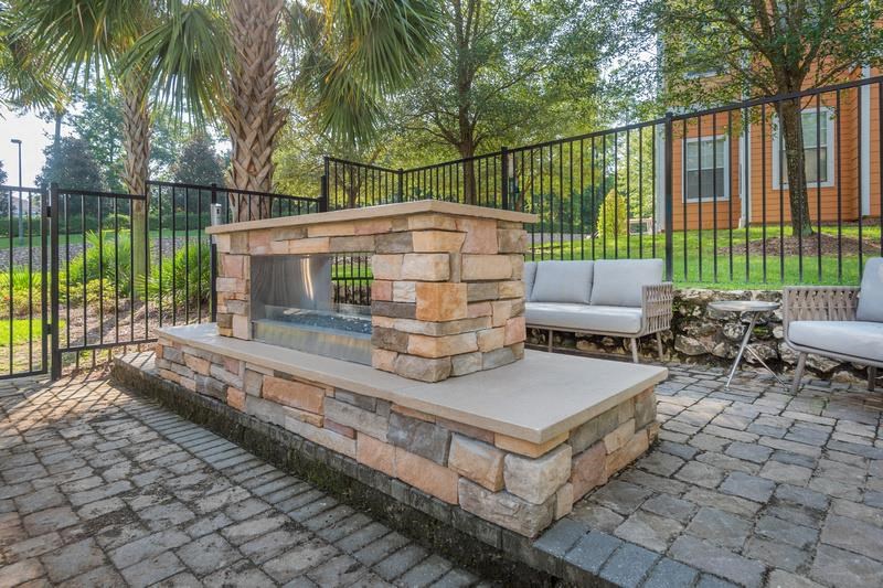 Tallahassee FL apartment complex grilling pavilion with two grills, lounge chairs, brick flooring, and a roofed sitting area at Evergreens at Mahan