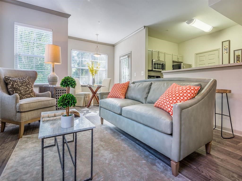 Furnished living room with ample seating, wood designed flooring, high ceiling and views of kitchen and breakfast bar at Evergreens at Mahan in Tallahassee, FL
