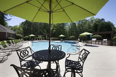 A wrought iron circular table with 4 chairs and umbrella sitting on the sudeck by the pool at TEN35 Alexander Apartments