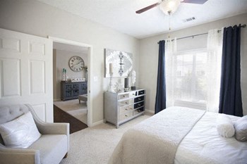Model bedroom furnished with a large bed, chair and dresser at TEN35 Alexander Apartments in Augusta, GA