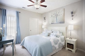 Model bedroom furnished with a large bed, nightstand and desk with a chair at TEN35 Alexander Apartments in Augusta, GA
