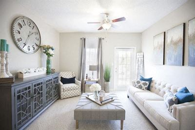 Model living room furnished with a large couch, coffee table and chair at TEN35 Alexander Apartments