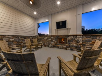 Cozy outdoor lounge area with fireplace and television at The Station at Brighton in Grovetown, GA