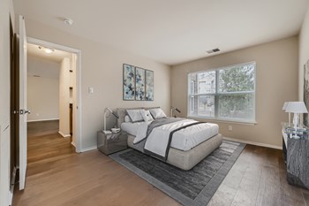 Bedroom with wood-designed flooring and large window at Hunt Club apartments for rent - Photo Gallery 9