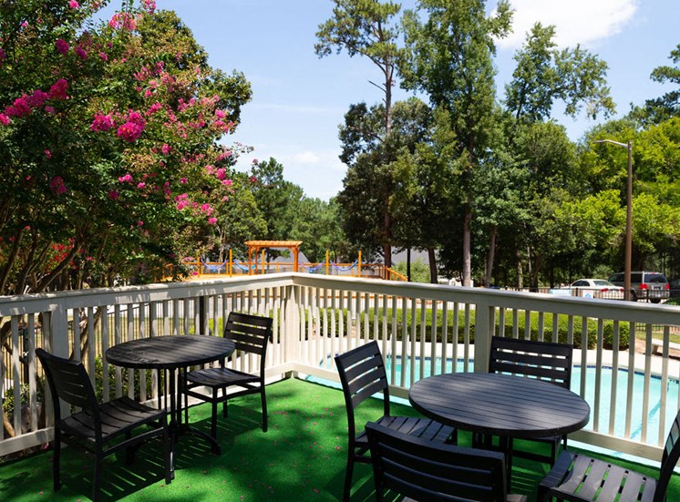 balcony with black tables and chairs overlooking pool area at Macon GA apartments