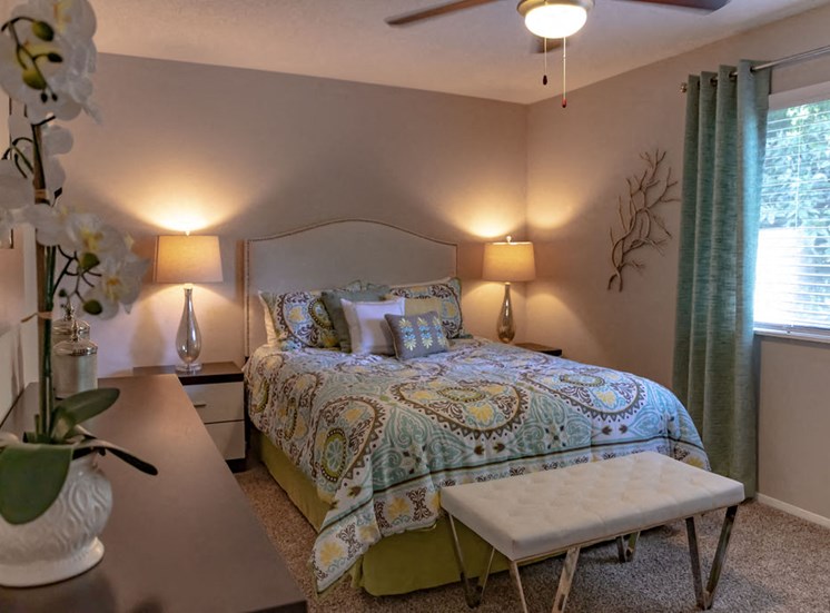 furnished apartment bedroom with neutral carpet ceiling fan and window