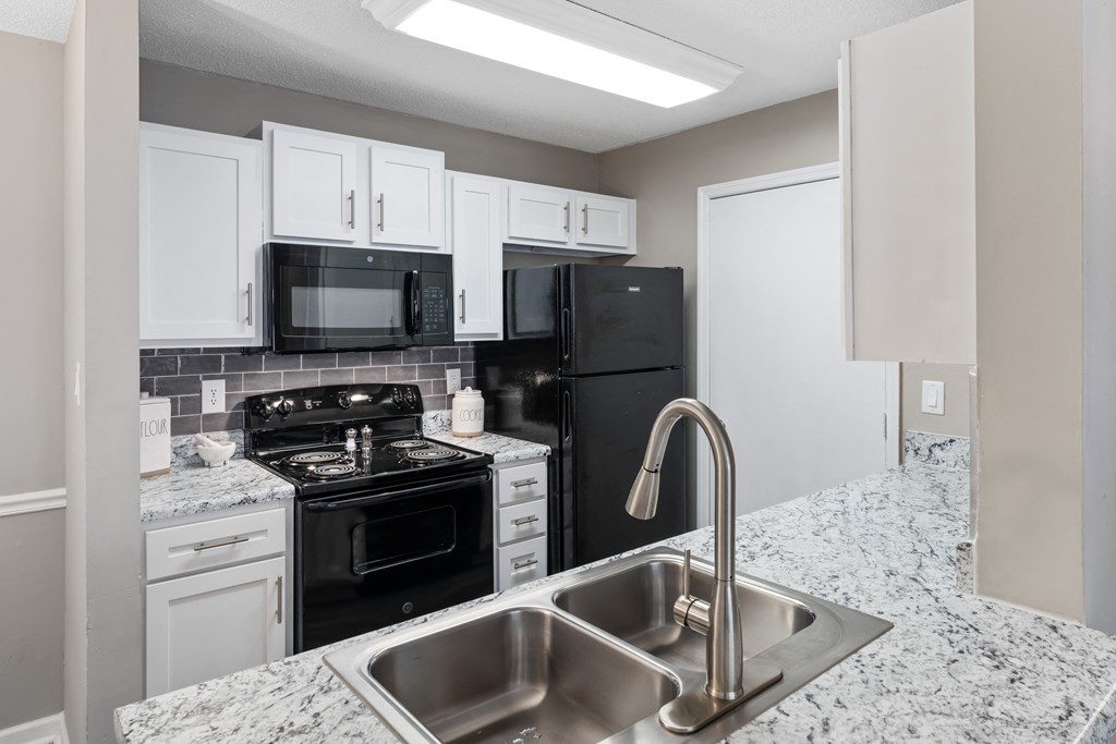 a kitchen with white cabinets and black appliances