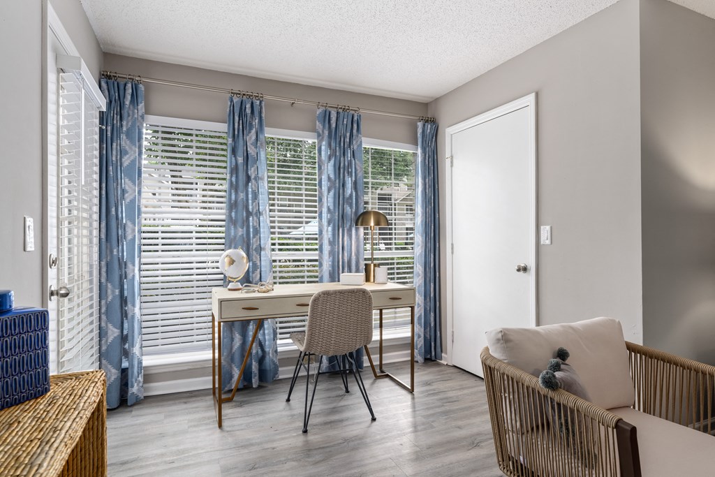 a desk with a chair and a lamp in a room with a couch and a door