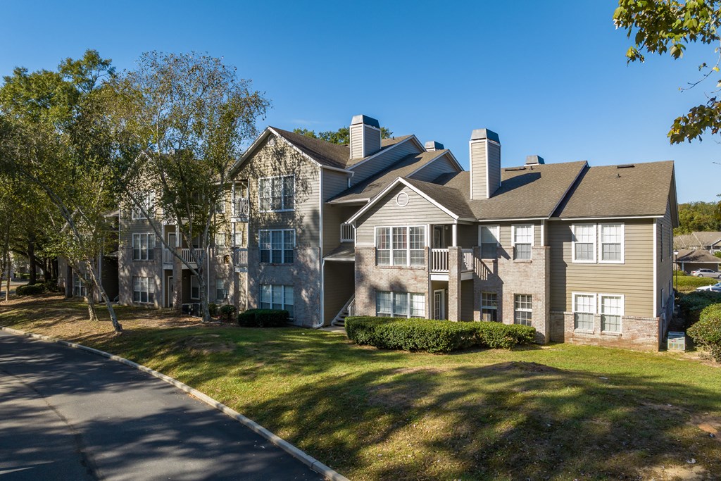 a large apartment building with a lawn and trees