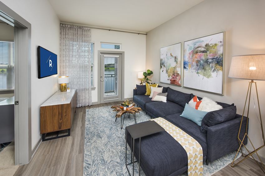 Living room with wood-designed flooring and door to balcony at Ravella at Town Center in Jacksonville, FL - Photo Gallery
