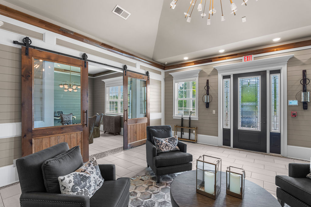 A living room with a black couch and a glass door.