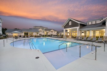 Resort-style swimming pool with shallow wading area and clubhouse patio at twilight at the Station at Savannah Quarters in Pooler, GA - Photo Gallery 2