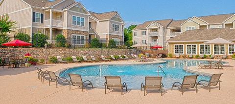 a pool with chairs and umbrellas in front of apartment buildings