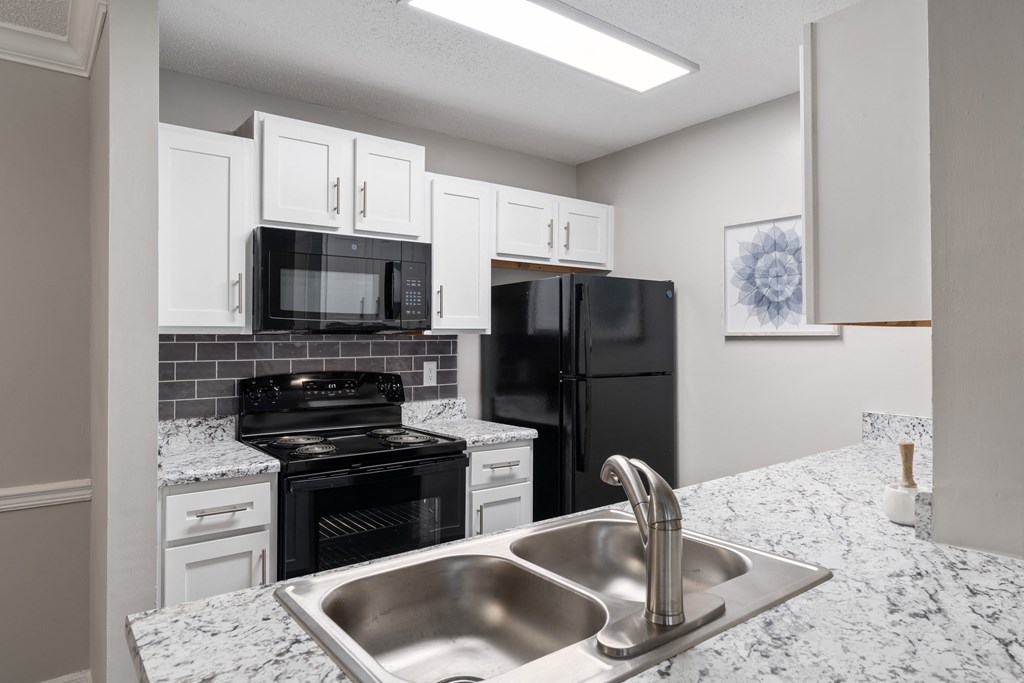 a kitchen with white cabinets and black appliances