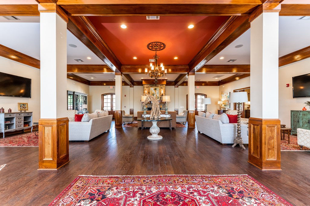 Interior of the resident clubhouse and leasing center with grand entry, sofas, TVs and fireplace at Riverstone apartments for rent in Macon, GA