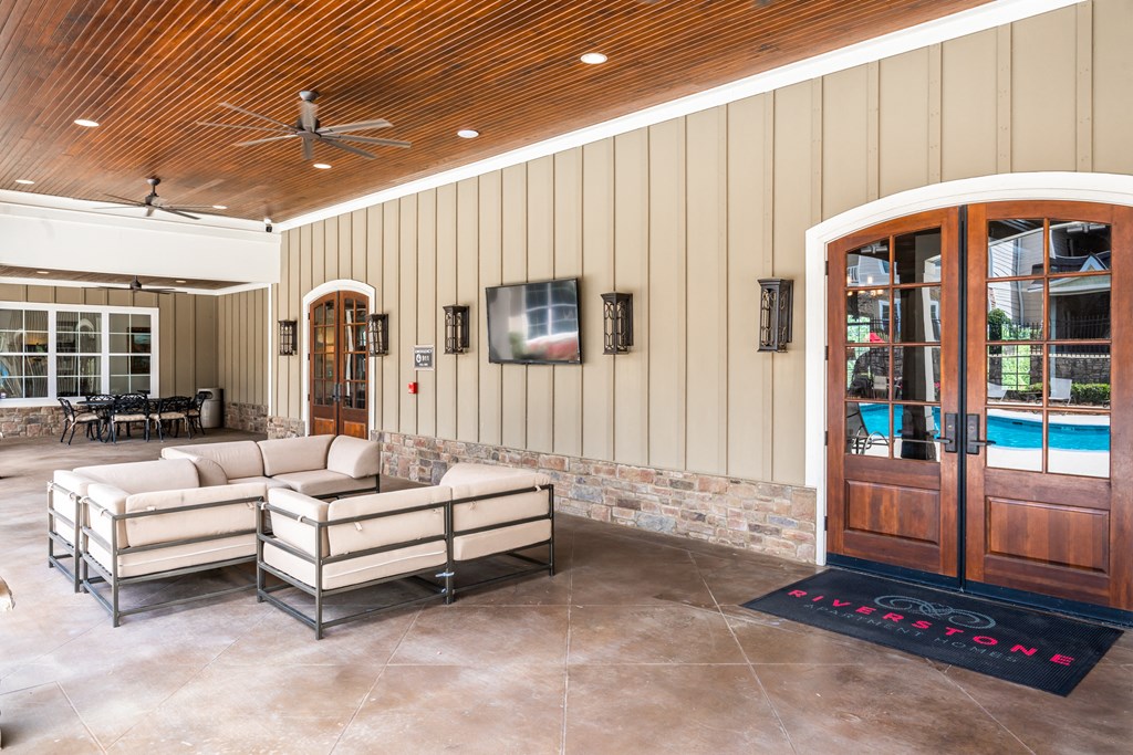Back patio of clubhouse with outdoor furniture and TV at Riverstone apartments for rent in Macon, GA