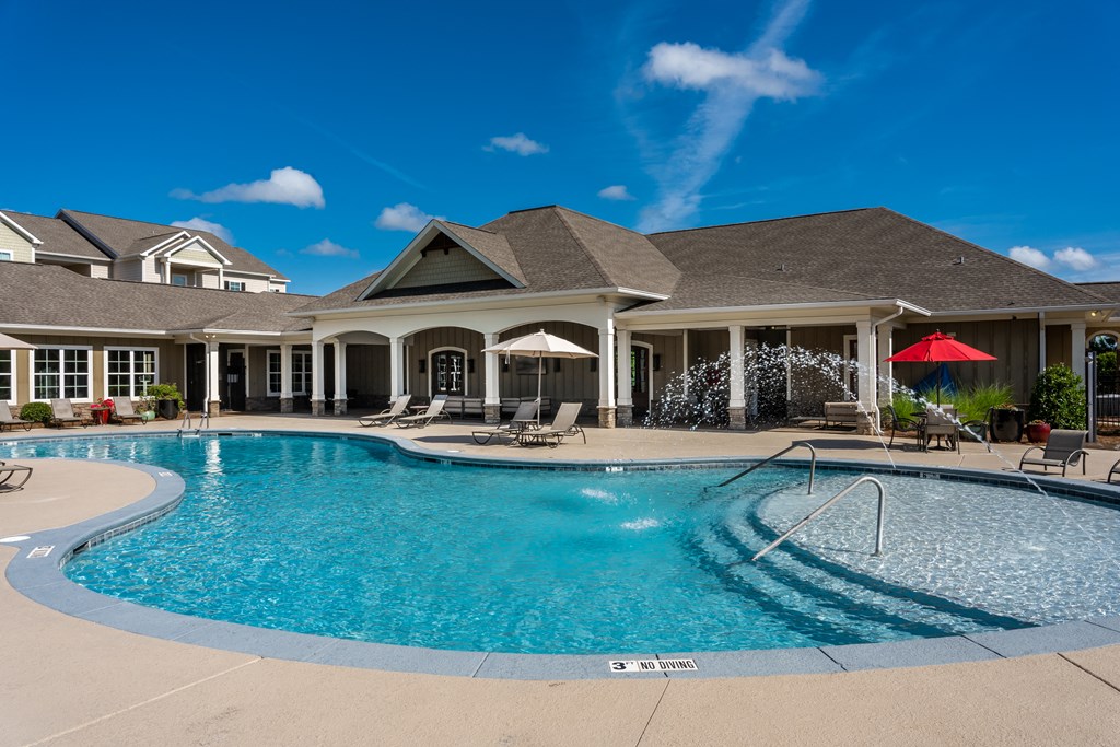 Resort-style swimming pool with view of clubhouse at Riverstone apartments in Macon, GA