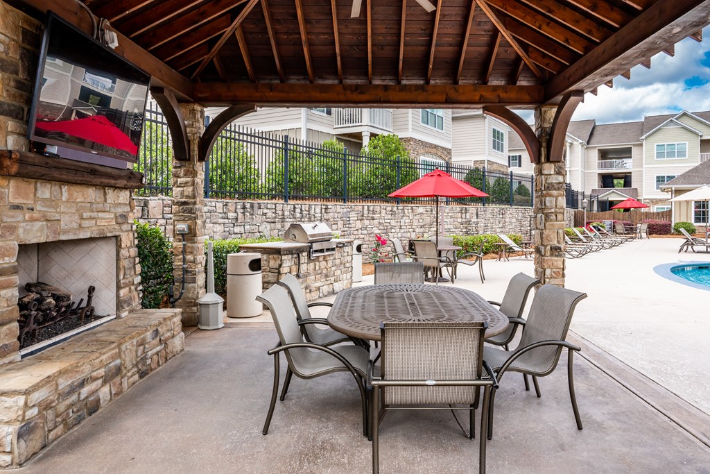 Poolside pavilion with table and six chairs, fireplace and large TV at Riverstone apartments for rent in Macon, GA