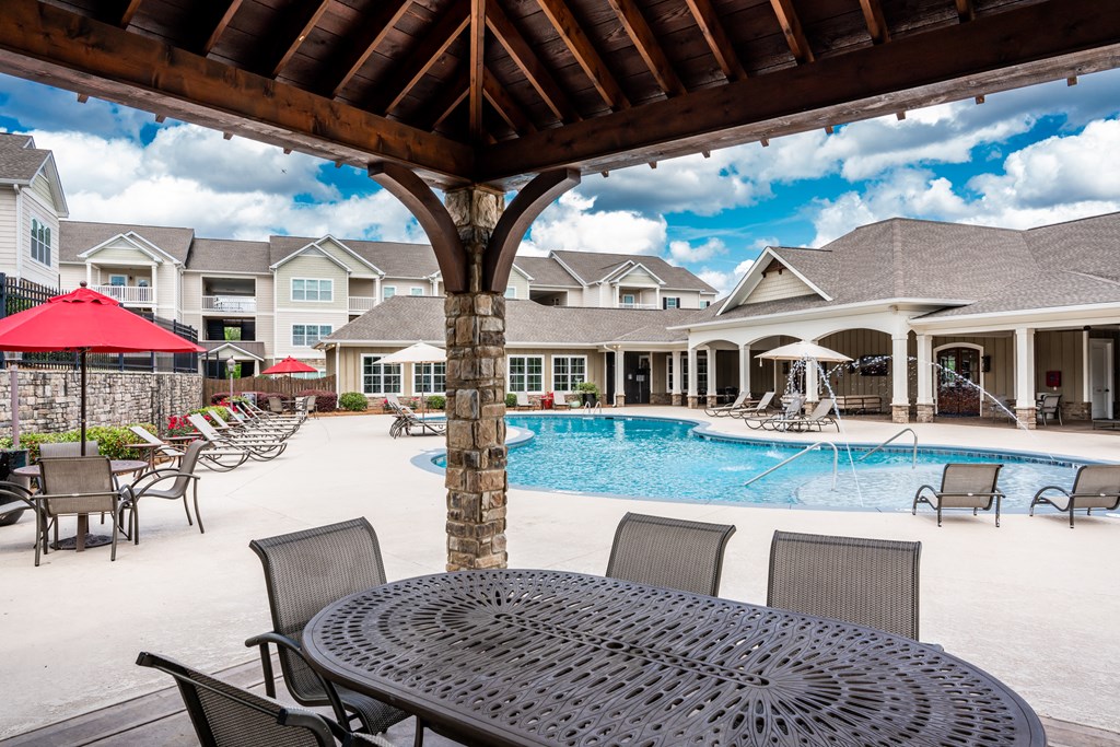 View of outdoor swimming pool and clubhouse under the poolside pavilion at Riverstone apartments for rent in Macon, GA