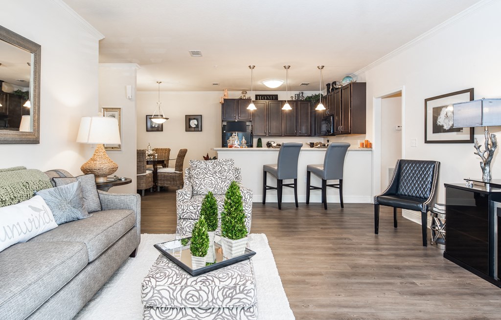 Open-concept living room with chairs and couch with view of dining area and kitchen at Riverstone apartments for rent in Macon, GA