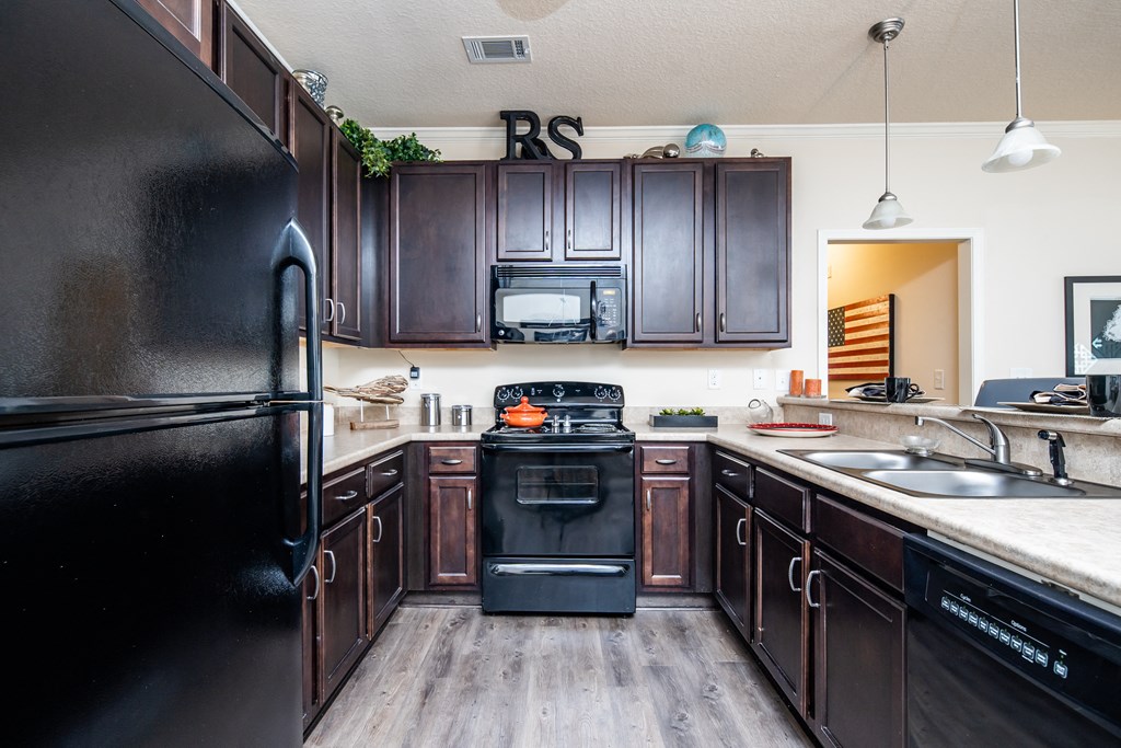Kitchen with sleek black appliances and dark wood cabinetry at Riverstone apartments for rent in Macon, GA