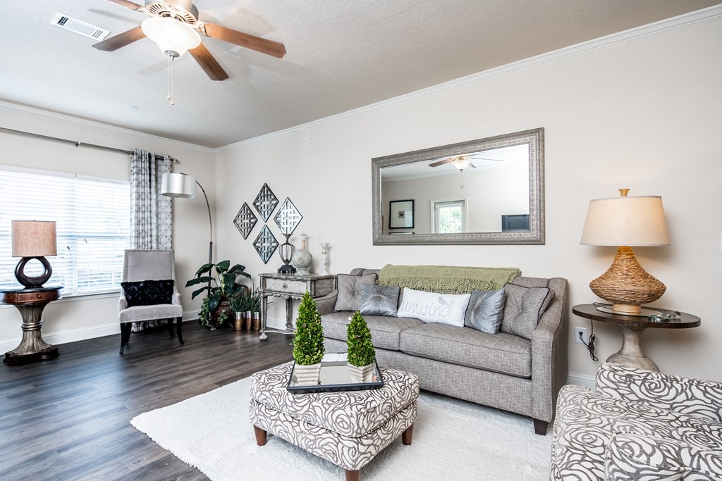 View of furnished living room with wood-designed flooring, ceiling fan and window at Riverstone apartments for rent in Macon, GA