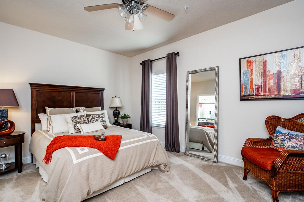 Furnished master bedroom with ceiling fan, carpet flooring, and window at Riverstone apartments for rent in Macon, GA