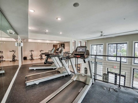 the gym is equipped with cardio equipment and a large window