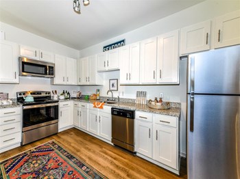 Kitchen with stainless steel appliances, white shaker-style cabinets, and granite-style counters at Exchange at Windsor Hill in North Charleston, SC - Photo Gallery 3