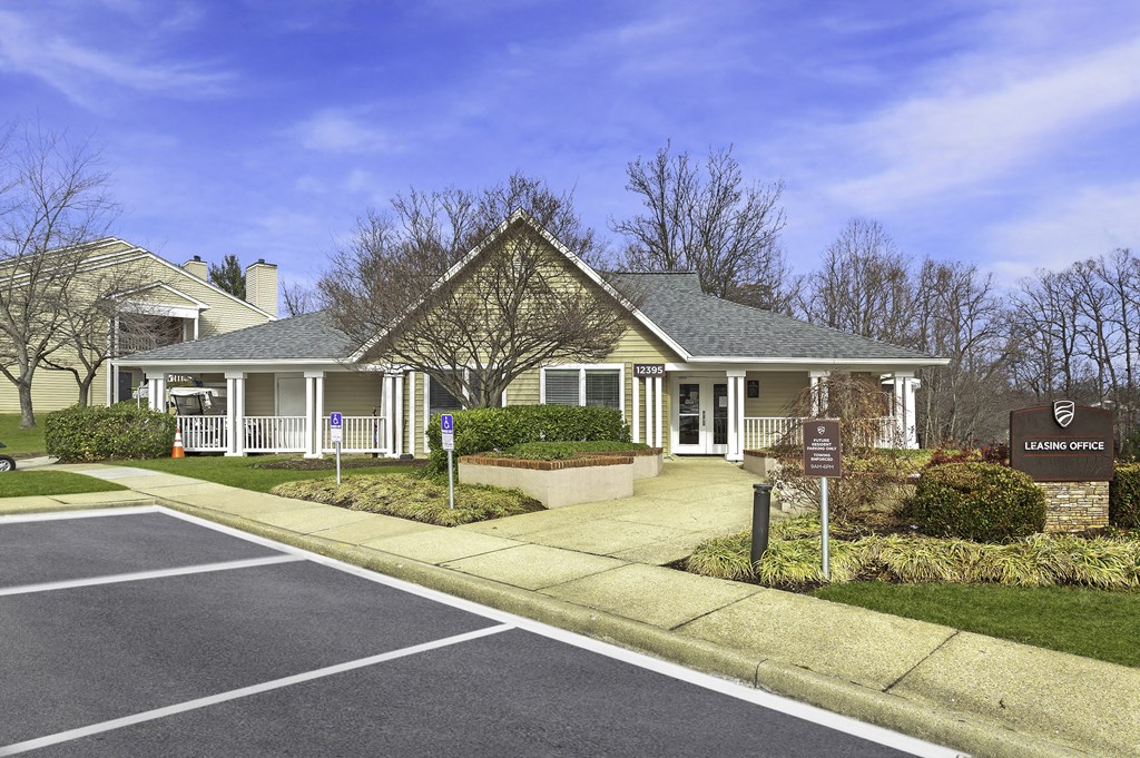 Front entrance of the leasing office with parking spaces and lush landscaping at Springwoods at Lake Ridge