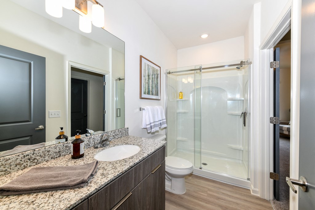 Model bathroom with wide, granite vanity and walk-in shower at The Station at Brighton apartments
