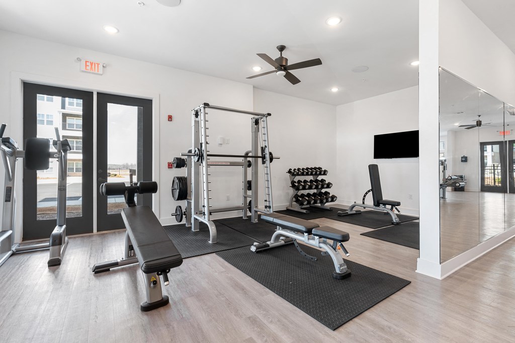 a gym with exercise equipment and a ceiling fan