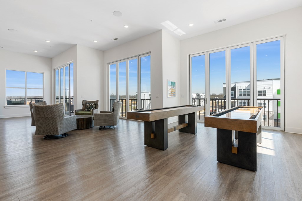 a game room with a pool table and chairs and large windows