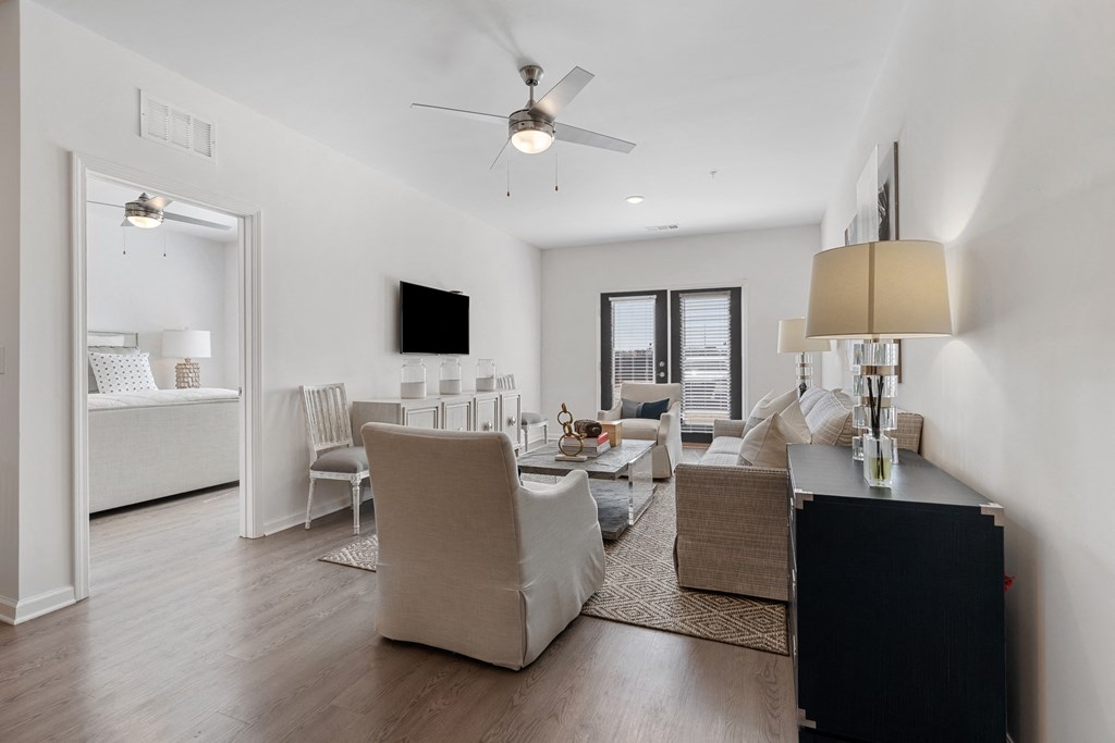 a living room with white walls and a ceiling fan